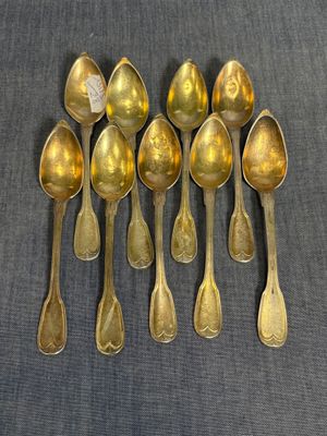 six cuillères en or sont alignées sur une table