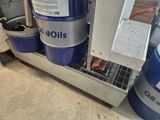 Plusieurs barils de pétrole sont empilés sur une étagère dans un garage.