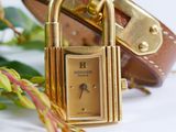 a gold watch with a padlock on it next to a bouquet of flowers