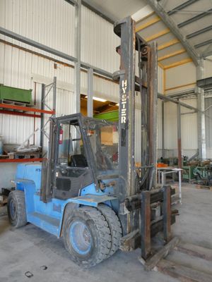 un chariot élévateur bleu dans un entrepôt, avec des palettes en arrière-plan