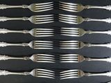 a lot of forks that are on a black table