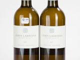 deux bouteilles de vin posées l'une à côté de l'autre sur une surface blanche