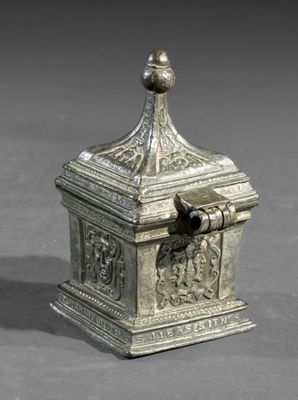 une vieille boîte en argent sur laquelle est posé un oiseau, posée sur une table