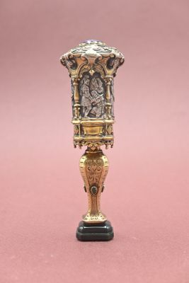a gold and black vase on a pink surface