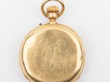 an antique gold pocket watch on a white surface with a white background