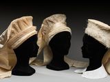 trois têtes de mannequin sont alignées les unes à côté des autres sur une surface grise