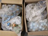 deux boîtes remplies de décorations bleues et blanches posées par terre