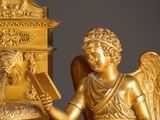 a statue of an angel reading a book next to a clock
