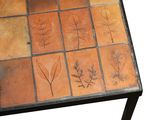 a table with a tile design on it with leaves on it