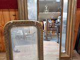 trois miroirs posés sur une table, avec un mur rouge en arrière-plan