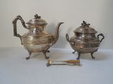 two silver teapots sitting next to each other on a table