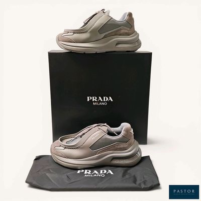 baskets Prada grises et blanches avec leur boîte, sur fond blanc
