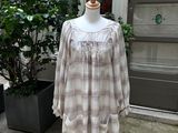 une robe à carreaux beiges et blancs posée sur un mannequin devant un immeuble
