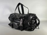 black leather duffel bag sitting on a white surface with a white background
