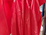 trois imperméables rouges suspendus à un porte-manteau dans un magasin