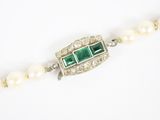 a close up of a necklace with pearls and emeralds