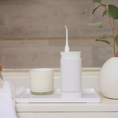 a white toothbrush sitting on a tray next to a candle