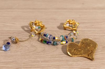 une broche en feuille d'or, des boucles d'oreilles et un bracelet posés sur une table en bois