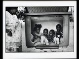 une photo en noir et blanc d'un groupe d'enfants assis devant un téléviseur