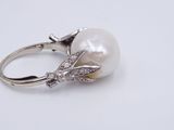 an image of a white pearl and diamond ring on a white surface