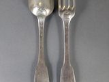 two silver spoons and a fork on a gray surface