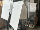 trois tableaux blancs sur un support dans une pièce