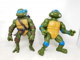 Deux jouets représentant des adolescents mutants sont disposés côte à côte sur une surface blanche