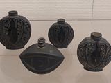 three black vases on display in a glass case