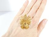 someone is holding a gold ring in their hand on a white surface