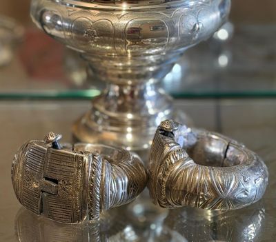 two silver rings on a glass table next to a silver vase