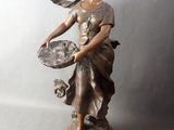 bronze statue of a woman holding a tray of food on a wooden base