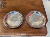 two silver plates on a wooden table with a flower design