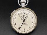 une montre de poche en argent posée sur une surface noire