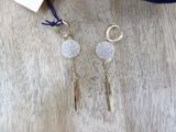 a pair of earrings with gold and silver beads on a wooden surface
