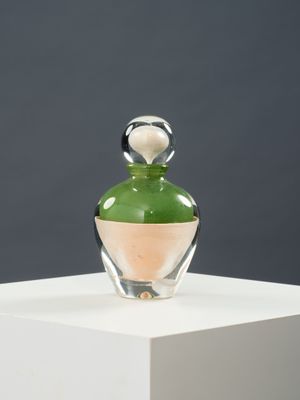 une bouteille en verre avec un bouchon vert posée sur un socle blanc