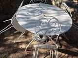 une table et des chaises blanches à l'ombre d'un arbre