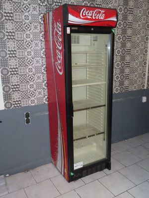 a coca cola cooler sitting in the corner of a room