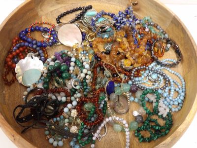 un bol en bois rempli d'un assortiment de perles et de colliers