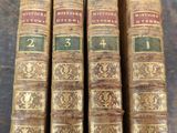 four old books sitting on top of a wooden table