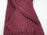a close up of a red knitted scarf on a white surface