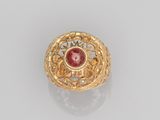 a gold ring with a red stone surrounded by filigree filigree