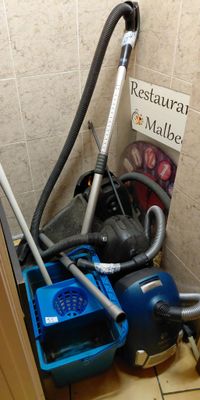 a blue vacuum and a blue bucket in the corner of a bathroom