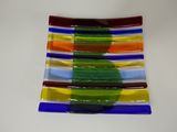 une assiette en verre multicolore posée sur une table blanche