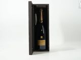 une bouteille de champagne dans un coffret en bois avec un tire-bouchon