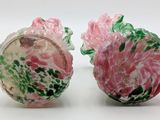 pair of pink and green glass vases on a white surface