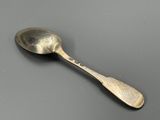 une vieille cuillère au manche en argent posée sur une table