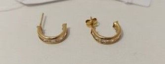 une paire de boucles d'oreilles plaquées or et un nœud papillon posés sur une table blanche