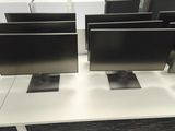 three computer monitors sitting on a white desk in a room