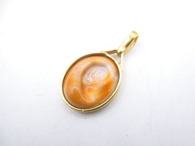 a close up of a gold plated pendant with an orange stone