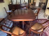 a dining room table with chairs and a rug on the floor
